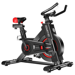 A black Powertrain heavy-duty exercise spin bike with red accents. It features a large flywheel, non-slip grip handlebars, and an adjustable saddle.