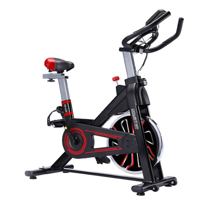 A red and black Powertrain RX-600 exercise spin bike with adjustable seat and handlebars, featuring an LCD display and a large flywheel.