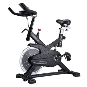 A black Powertrain RX-200 exercise spin bike with adjustable seat and handlebars, featuring an LCD display, large pedals with toe cages, and a powder painted steel frame.