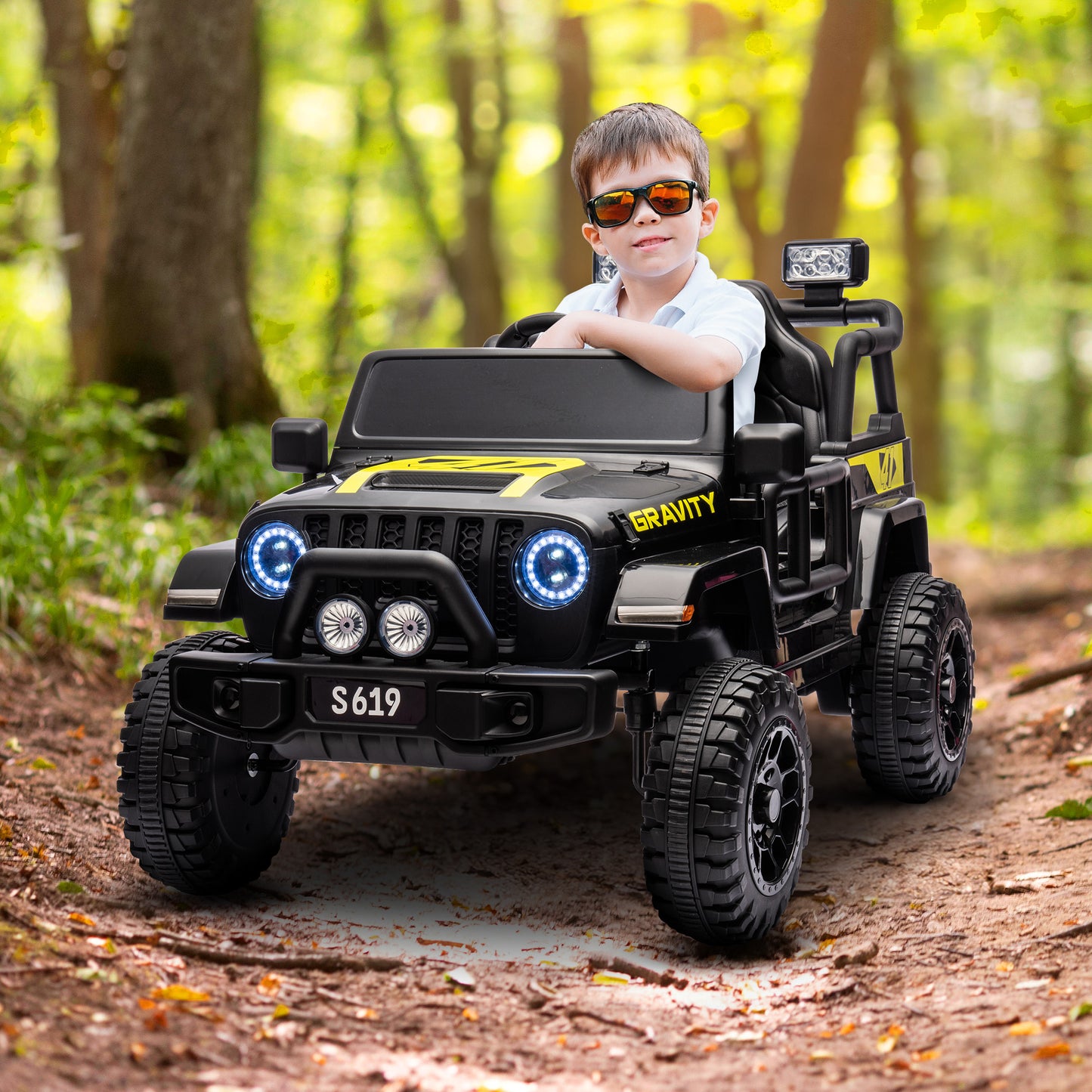 Child in sunglasses sitting in a toy truck in a forest
