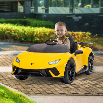 Child sitting in a yellow toy car on a paved area with greenery in the background