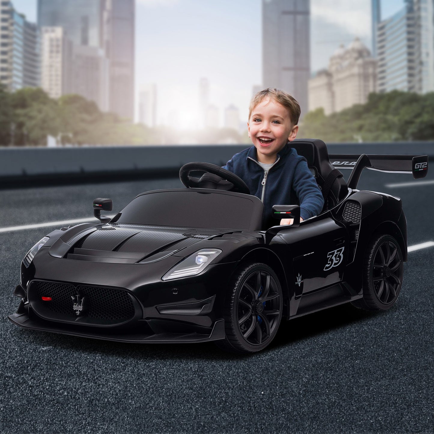 Child sitting in a black toy car with a cityscape background