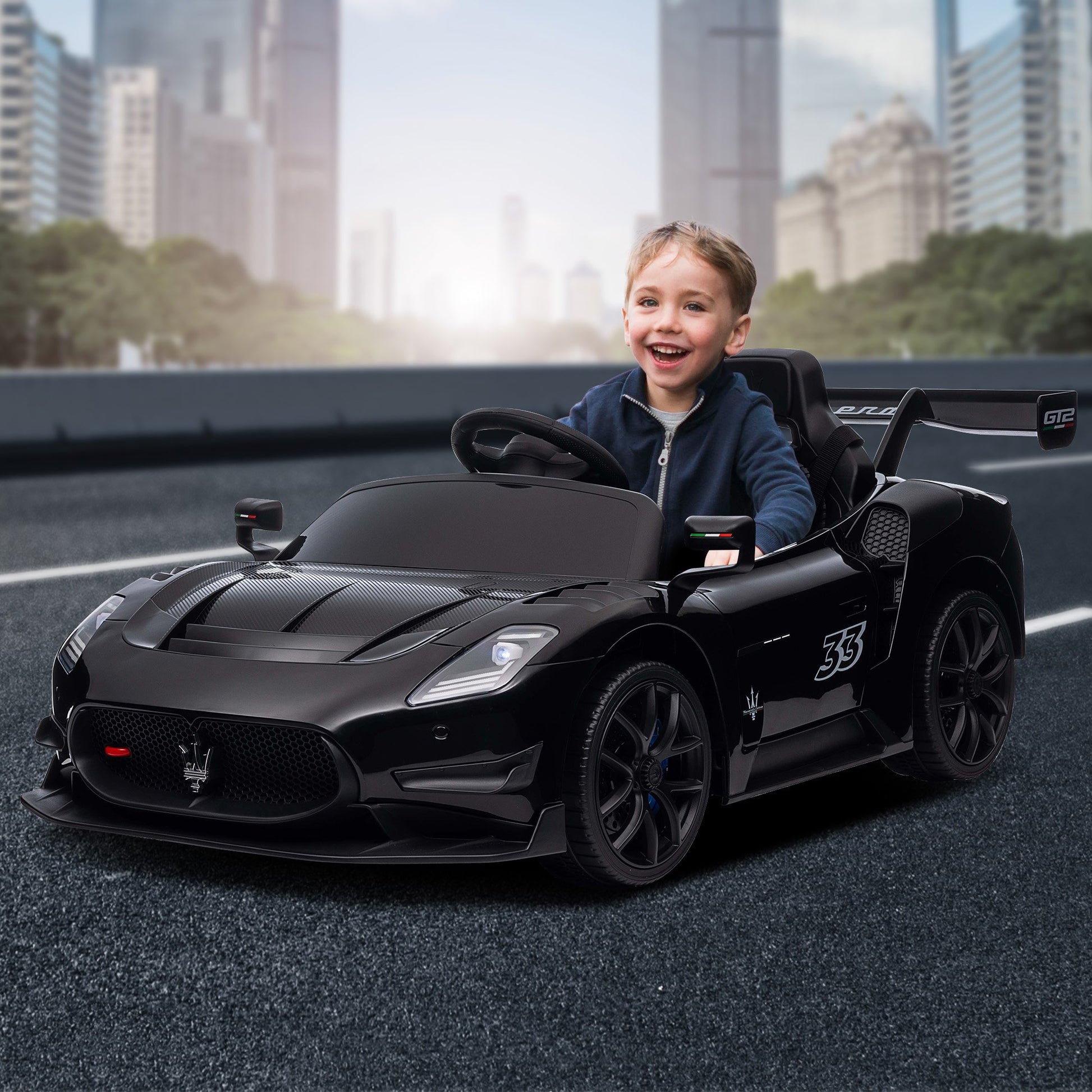 Child sitting in a black toy car with a cityscape background