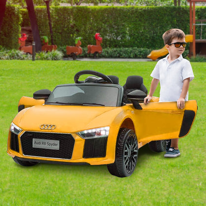 Child standing next to a yellow Audi toy car on grass