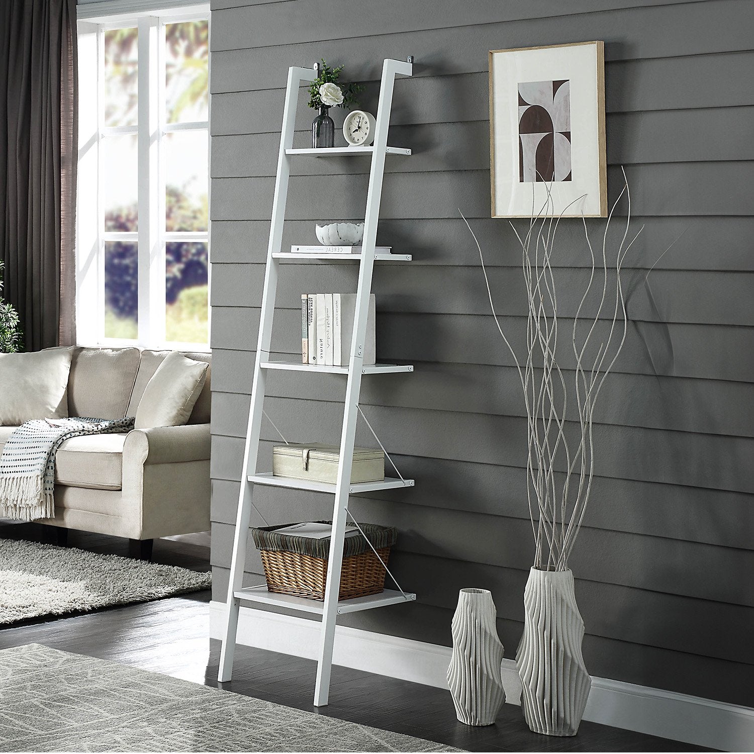 White ladder shelf against a gray wall with decorative items in a living room.