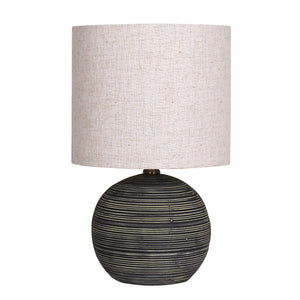 A ceramic table lamp with a striped pattern in antique black color, topped with a beige drum shade.