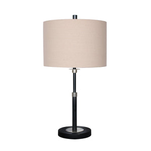 A table lamp with a black metal base and a beige linen drum shade.