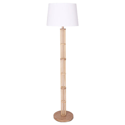 A Sarantino Rattan Floor Lamp with a ghost-white linen drum shade on a wood brushed metal base with a rattan body.