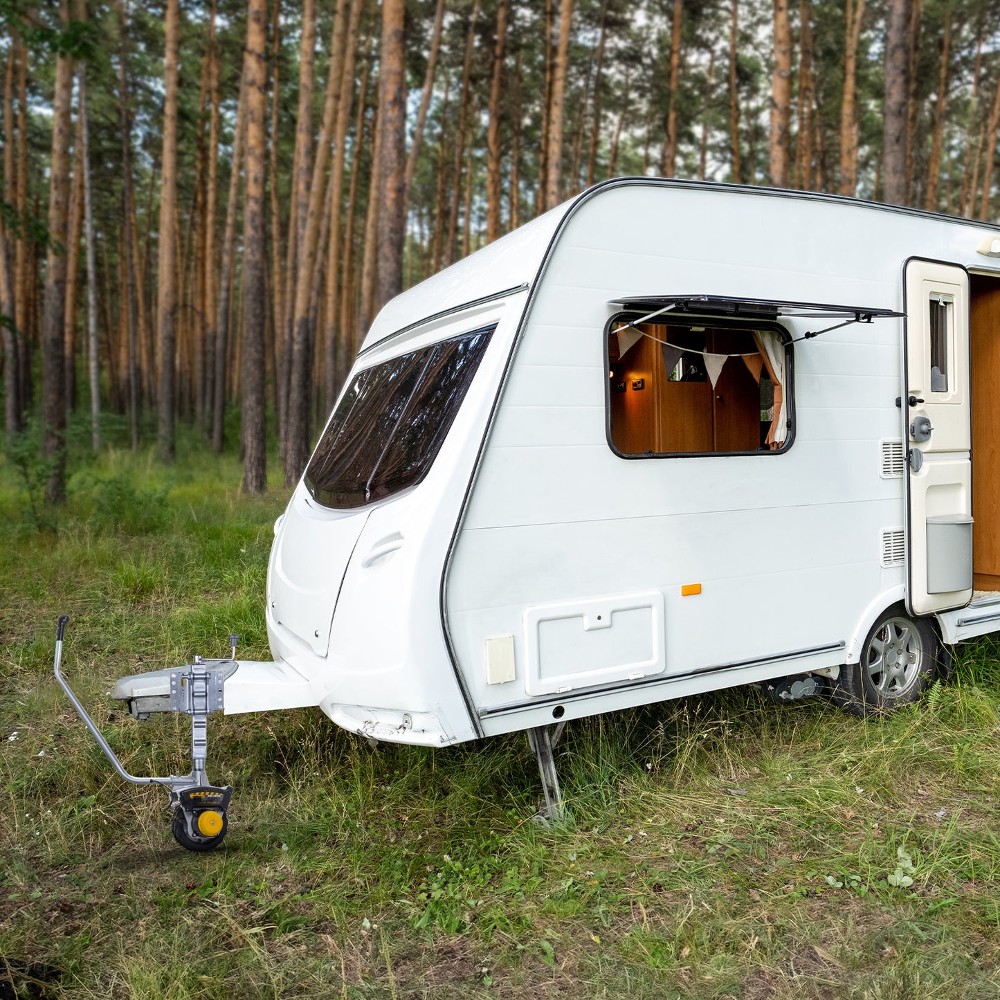 White caravan parked in a grassy area with trees in the background