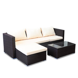 A 5-piece modular outdoor lounge set including a sofa, two armchairs, and an ottoman made of brown synthetic wicker with white cushions, alongside a rectangular coffee table with a glass top.