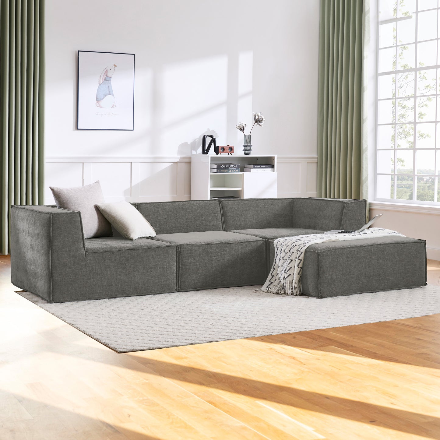 Gray sectional sofa in a modern living room with large windows and neutral decor.