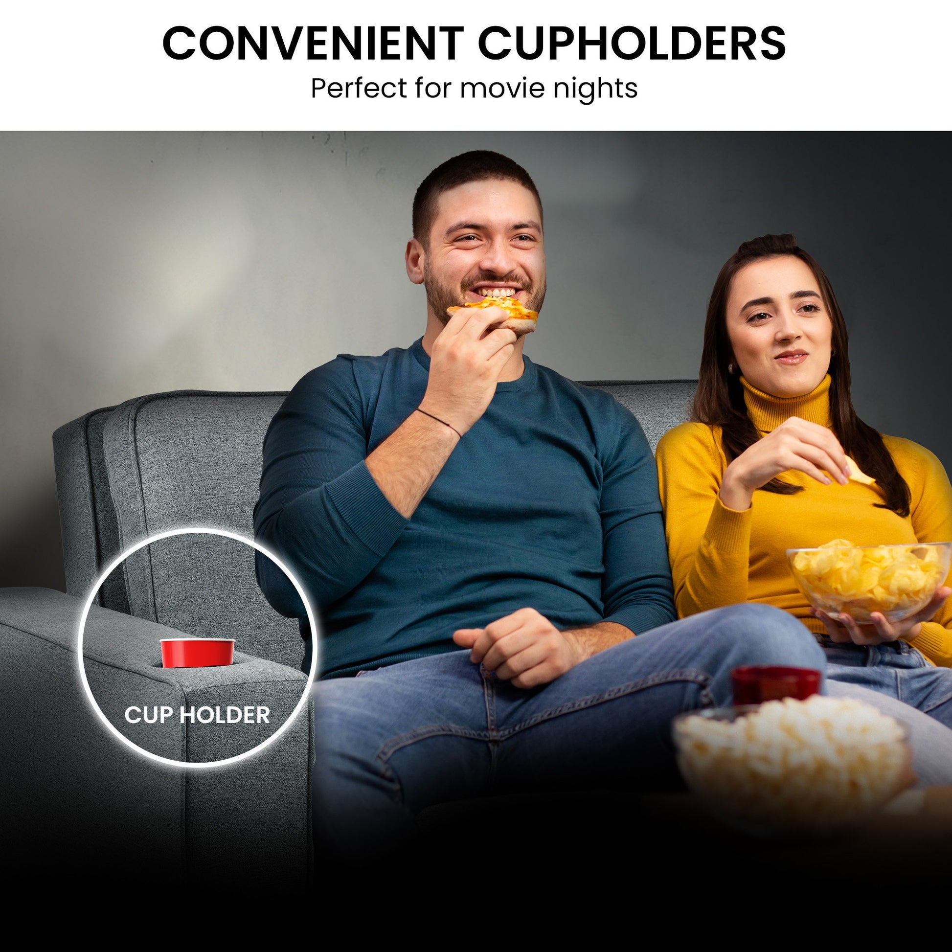 Man and woman sitting on a couch with cup holders, enjoying movie night.