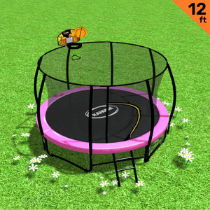 A 12ft round trampoline with a pink padding cover, safety enclosure net, black steel frame, and a ladder placed on grass with a few flowers around.