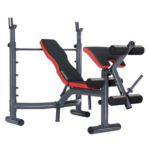 Adjustable weight bench with red and black padding, including an Olympic bar, preacher curl attachment, and leg curl extension.
