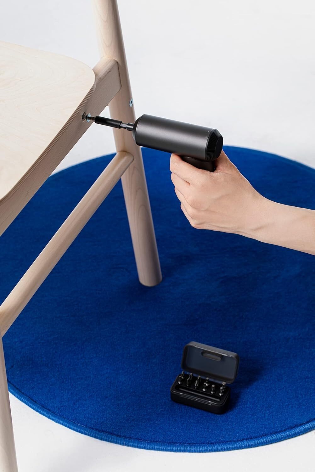 Hand using a black air pump to inflate a blue chair pad on a white background