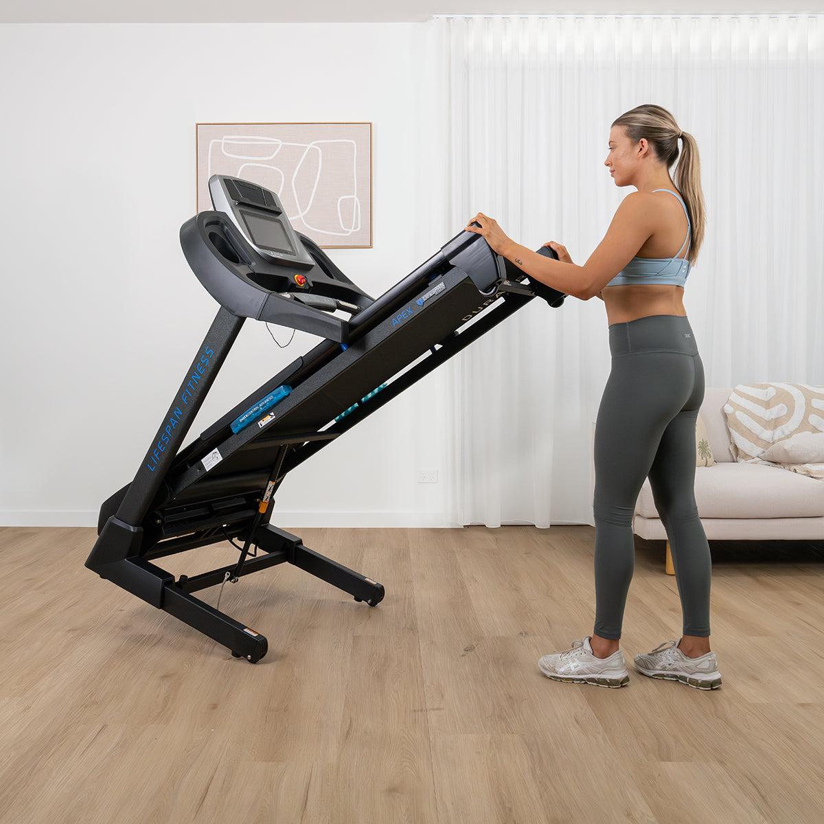Woman in athletic wear standing next to a treadmill in a home setting