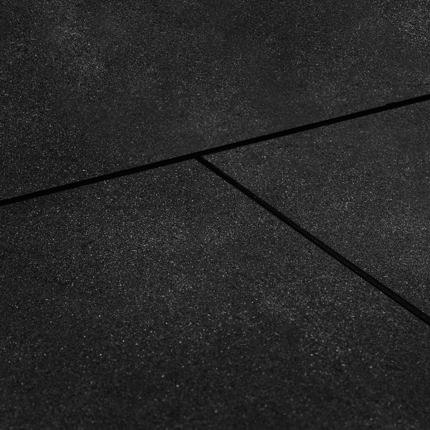 Close-up view of a black  rubber gym tile mat with a bevelled edge, showing the textured surface and slight crevice between mats.