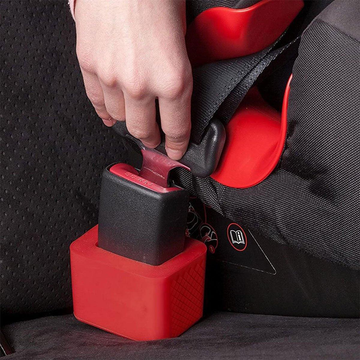 Person securing a red and black car seat with a strap.