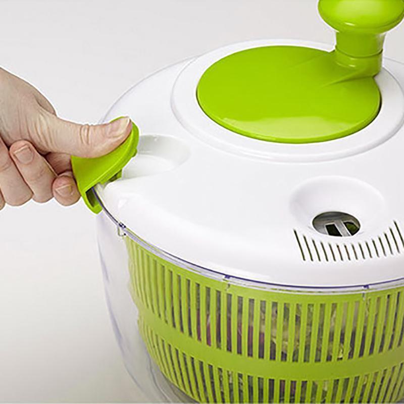 Green and white salad spinner being used on a white background