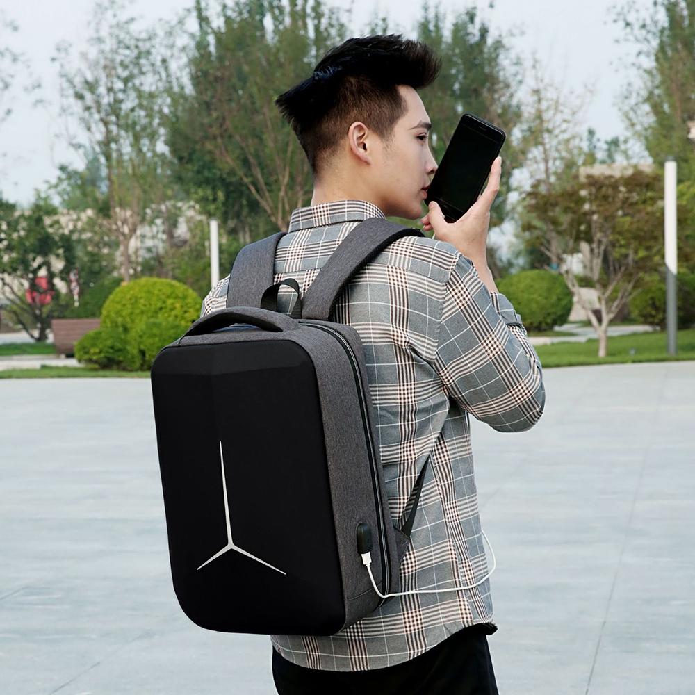 Person wearing a black backpack outdoors, holding a phone to their ear.