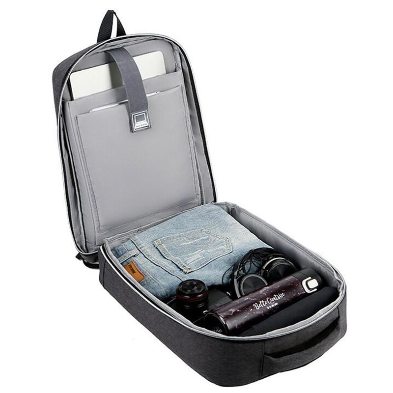 Open backpack with compartments containing a laptop, jeans, and other items on a white background