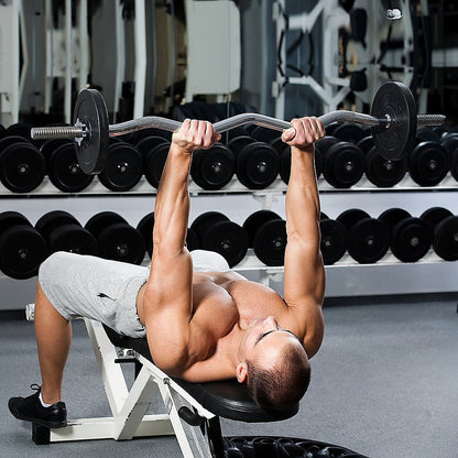 Man performing bench press with dumbbells in a gym setting