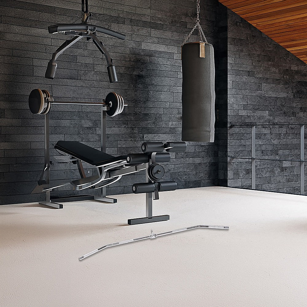 Gym equipment including a weight bench, barbell, and punching bag in a room with wooden ceiling.