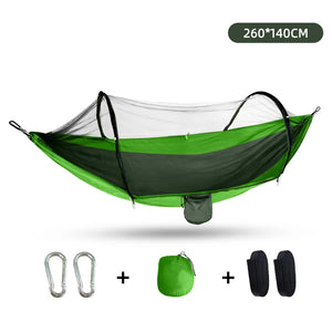 A green outdoor camping hammock with mosquito net, including metal carabiners, tree straps, and a compact storage pouch.
