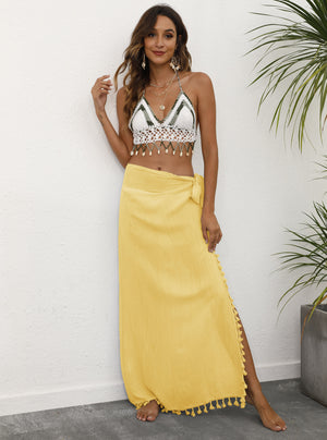 A woman wearing a yellow lightweight tassel sarong with tie design, styled as a wrap skirt.