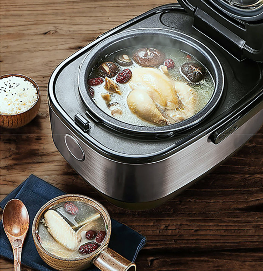 Electric hot pot with chicken and vegetables on a wooden table
