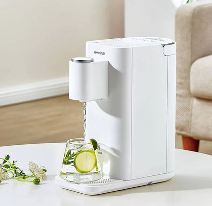 White electric water dispenser pouring water into a glass with lime and mint leaves on a white surface.