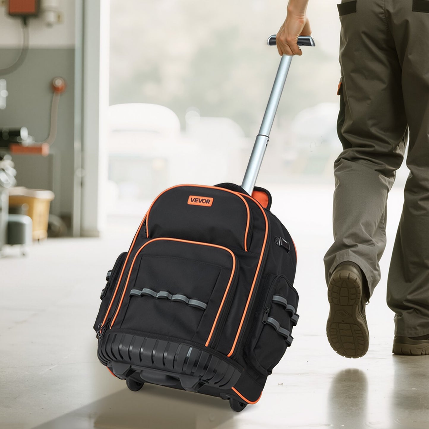 Black and orange rolling backpack with a person pulling it indoors.