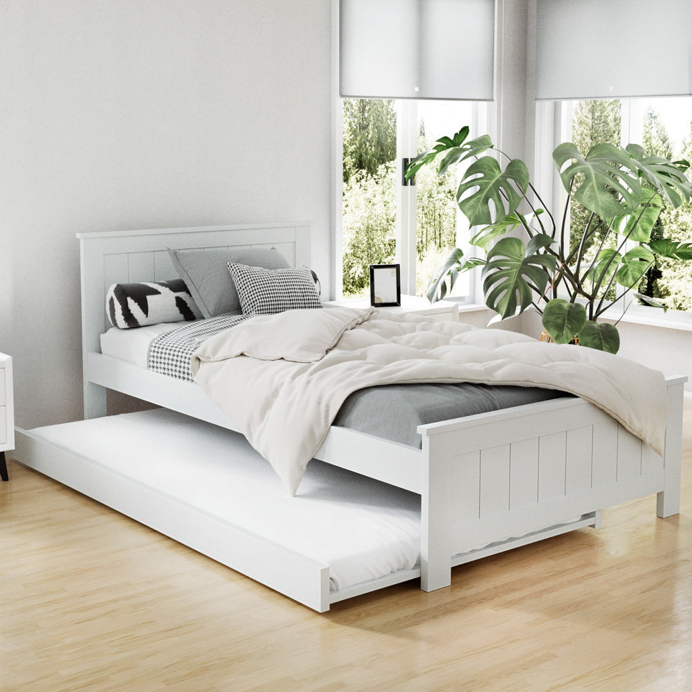 A white wooden trundle bed frame with timber slats, designed to fit under a king single bed, situated in a room with decor.