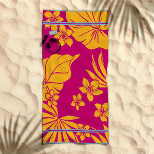 A brightly colored beach towel with a floral and nautical design laid out on a sandy beach.